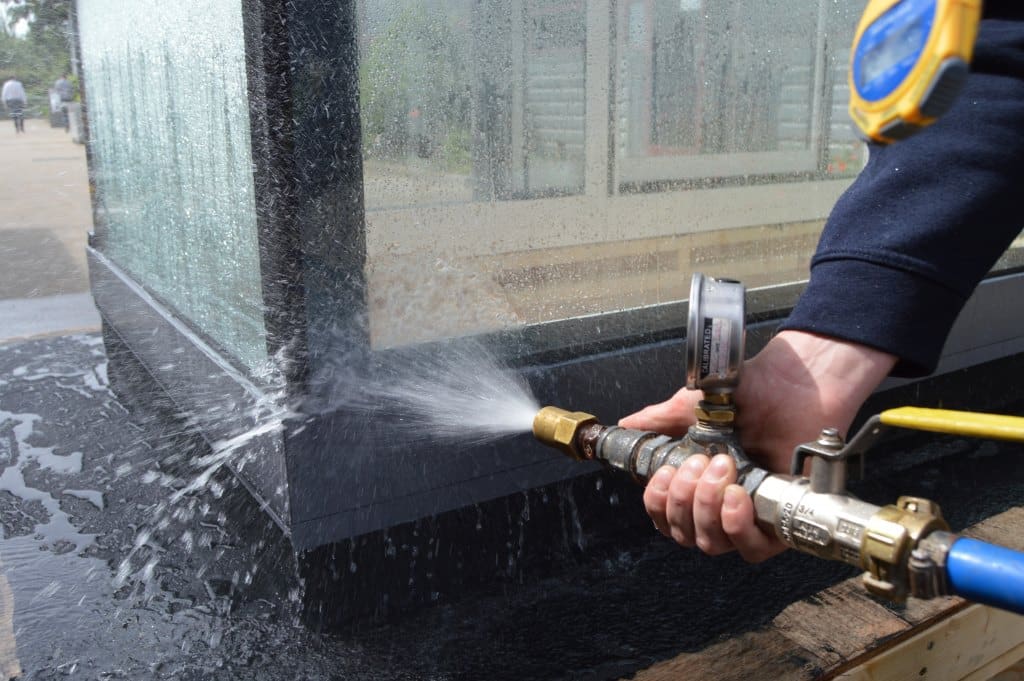 man spraying a box rooflight with a hose